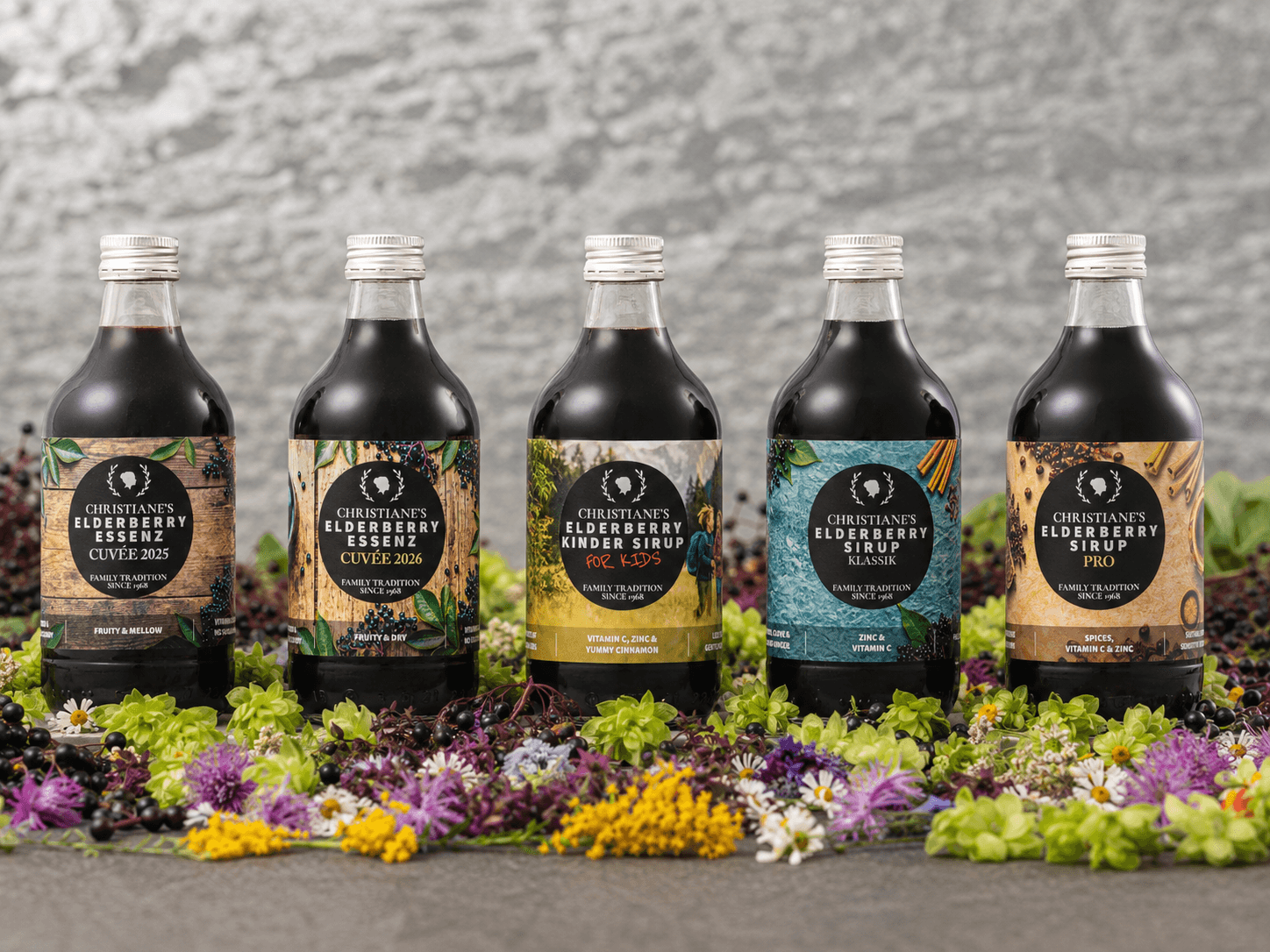Christiane's elderberry sirups and essences arrayed on a stone wall with elderberries and Austrian herbs